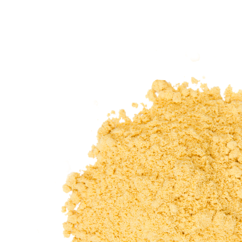 A close-up of fine yellow powder piled in the lower-right corner on a plain white background.