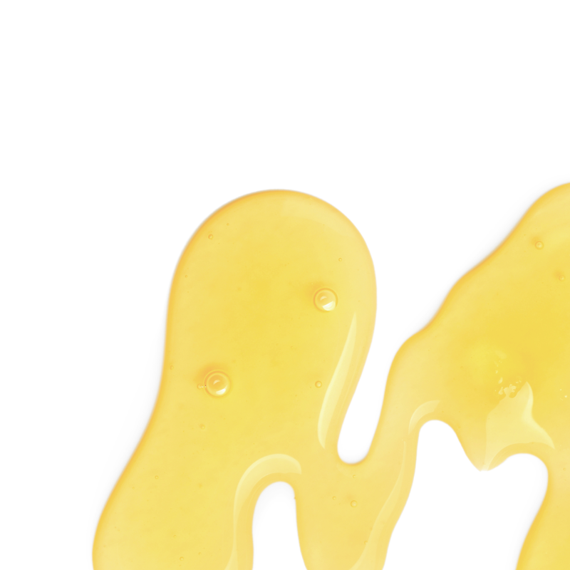 A close-up of a glossy, translucent golden-yellow MCT oil flowing on a solid white background.